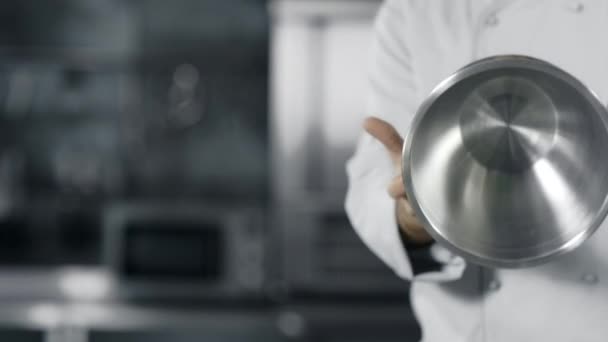 Chef kezek szórakozik az acél edény lassú mozgásban. Chef ember készül főzni - Felvétel, videó