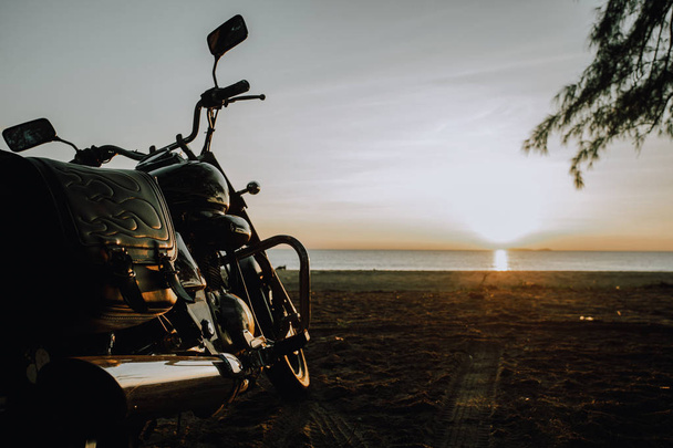 motorkerékpár parkolt a tengerparton a napfelkeltét. - Fotó, kép
