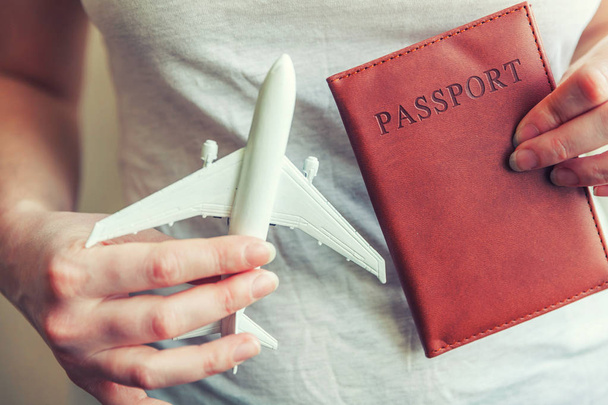 Tourist essentials. Female woman hands holding small toy model plane and passport - Photo, Image