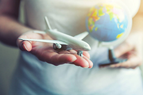 Mulheres mãos segurando pequeno modelo de brinquedo avião e mapa globo
 - Foto, Imagem
