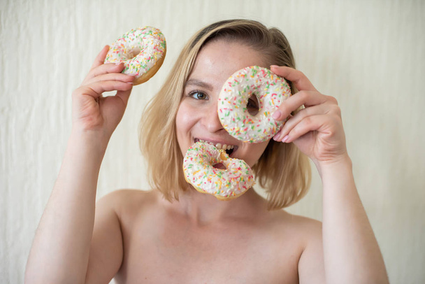Nude young woman eating donuts. Portrait of an attractive woman with a mountain of donuts - Foto, Bild