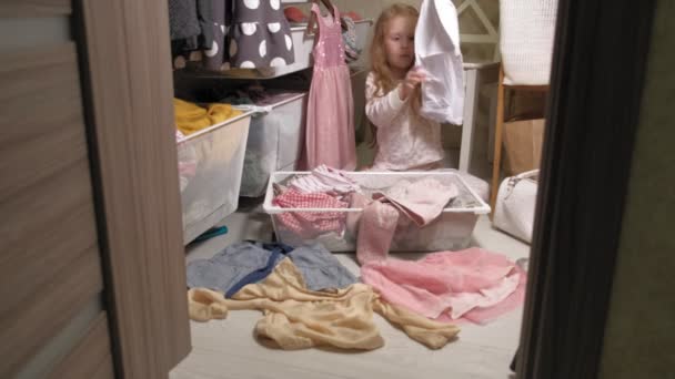 Holčička uklízí šaty v domácím šatníku - Záběry, video