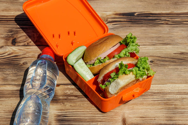 Bottle of water and school lunch box with two homemade burgers - Photo, Image