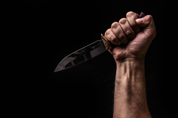 Hunting knife in hand on dark background - 写真・画像