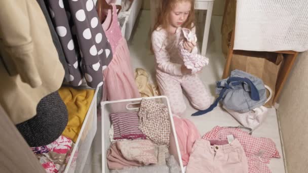 Holčička uklízí šaty v domácím šatníku - Záběry, video
