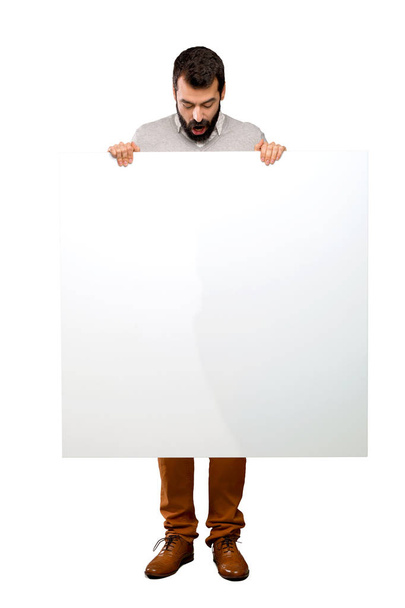 Hombre guapo con barba sosteniendo un cartel vacío sobre un fondo blanco aislado
 - Foto, imagen