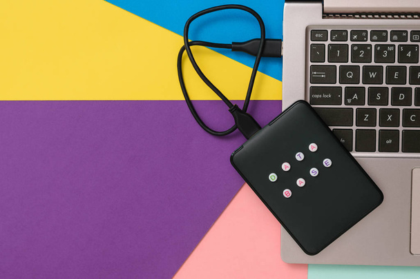 External hard drive with laptop on colorful background. Flat lay. The concept of backup storage. - Photo, Image