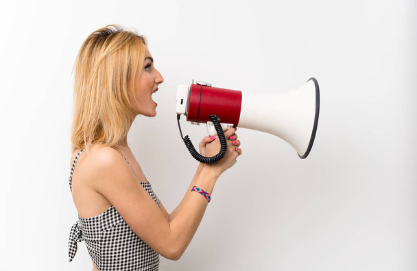 Mladá blondýna žena přes izolované bílé křičí přes megafon - Fotografie, Obrázek