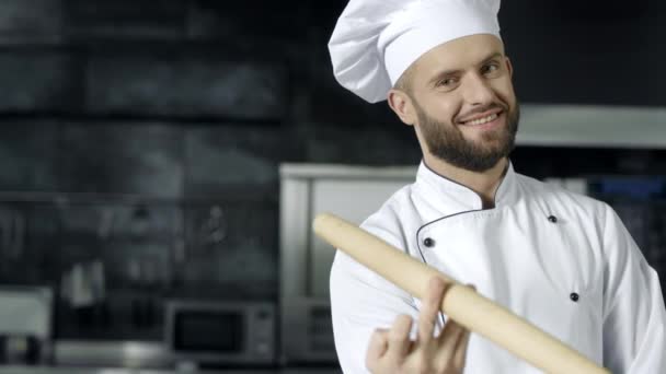 Chef hombre posando con rodillo en la cocina. Chef sonriente jugando con el rodillo
 - Metraje, vídeo