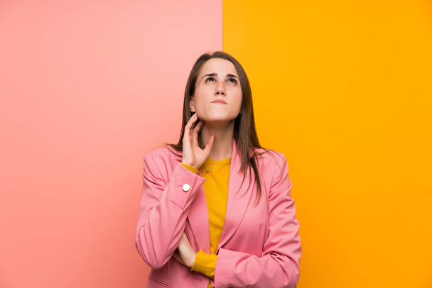 Young woman with pink suit over colorful background standing and thinking an idea - Фото, зображення