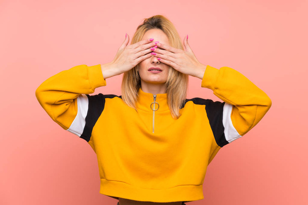 Mladá blondýna žena přes izolované růžové pozadí pokrývající oči rukama - Fotografie, Obrázek
