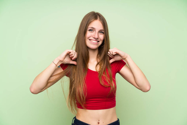 Молода жінка з довгим волоссям над ізольованою зеленою стіною пишається і самозадоволена
 - Фото, зображення