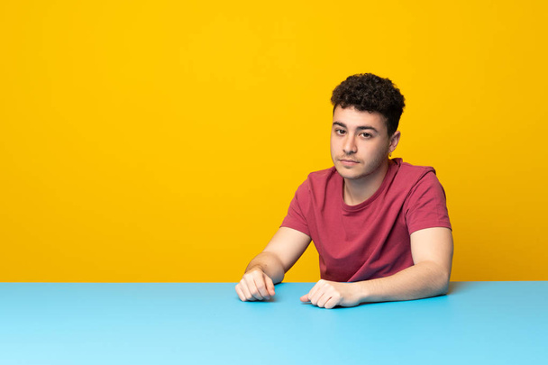 Young man with colorful wall and table portrait - Foto, immagini