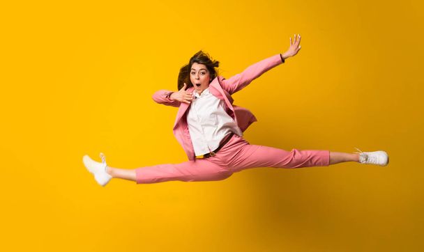 Nuori nainen hyppää yli eristetty keltainen seinä
 - Valokuva, kuva