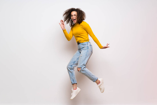 Dominican woman with curly hair jumping over isolated white back - Foto, imagen