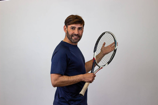 Portrait of handsome young man playing tennis holding a racket w - Fotó, kép