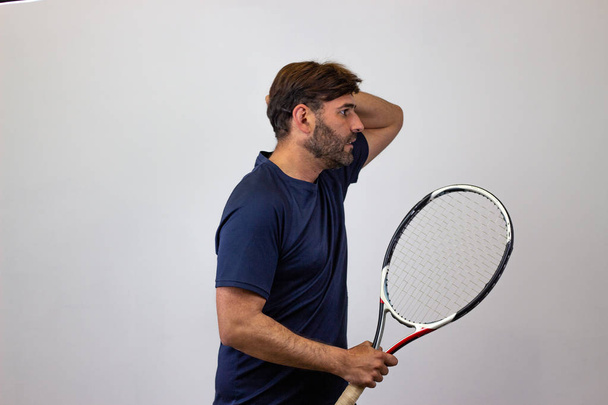 Πορτρέτο του όμορφος νέος άνθρωπος παίζοντας τένις κρατώντας μια ρακέτα w - Φωτογραφία, εικόνα