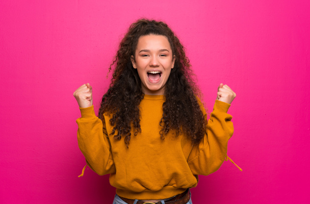 Ragazza adolescente sul muro rosa che celebra una vittoria nella posizione del vincitore
 - Foto, immagini