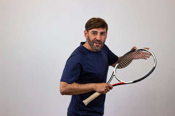 Portrait of handsome young man playing tennis holding a racket w - Foto, imagen