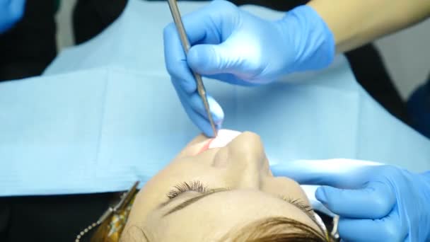 No gabinete de prática profissional. O dentista examina o paciente de perto. Doutor detém ferramentas dentárias - espelho. vista superior. 4k
 - Filmagem, Vídeo
