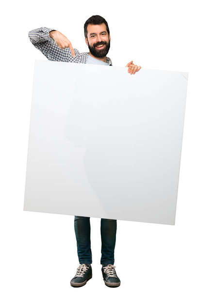 Happy Handsome man with beard holding an empty placard over isolated white background - Fotografie, Obrázek