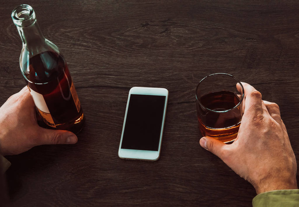 Człowiek posiadający szklankę whisky i butelkę alkoholu, na - Zdjęcie, obraz