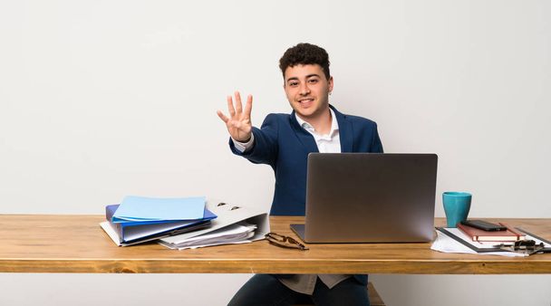 Бізнесмен в офісі щасливий і рахуючи чотири пальцями
 - Фото, зображення