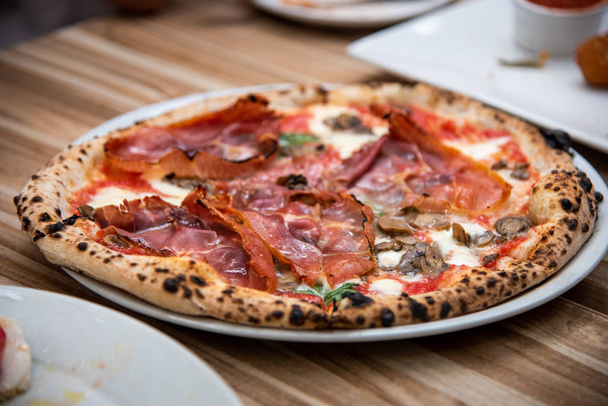 Percuitto pizza on wooden table, Italian cuisine in Vancouver, C - Fotó, kép
