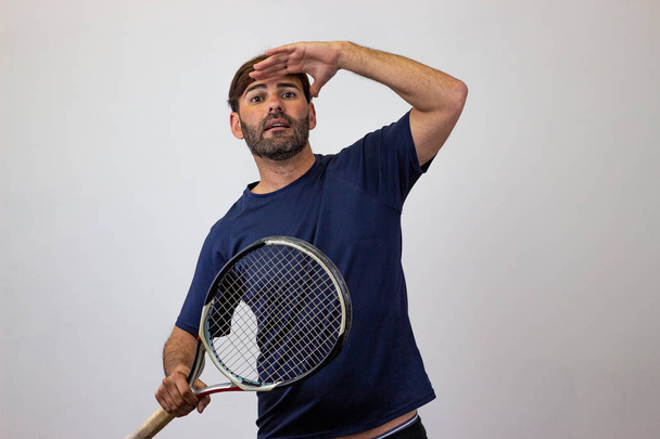 Portrait of handsome young man playing tennis holding a racket w - Foto, Imagen