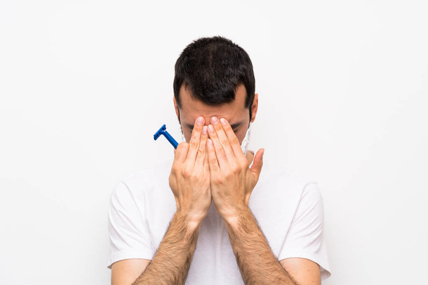 Muž si při holení vousy přes izolované bílé pozadí s unavené a zvrácený výrazem - Fotografie, Obrázek