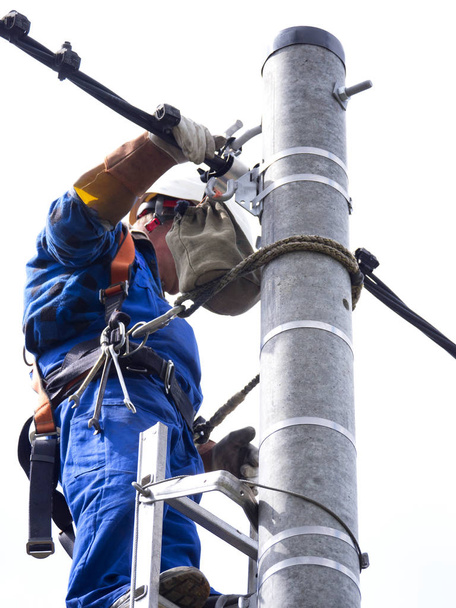 Arbeit eines Elektroinstallateurs an einem Strommast - Foto, Bild