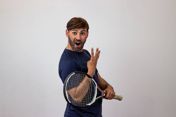 Portrét hezkého mladého muže, který hraje tenis a drží v ruce rámus w - Fotografie, Obrázek