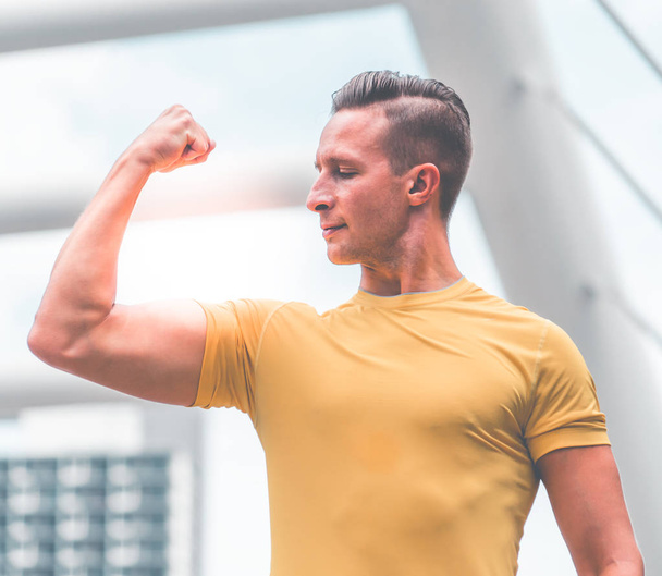 Portrait of sporty sexy man in yellow with raised arms, muscles  - Photo, Image