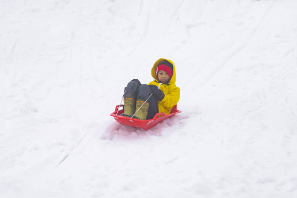 kleines japanisches Mädchen rutscht in Gala-Yuzaw den Schneesschlitten hinunter - Foto, Bild