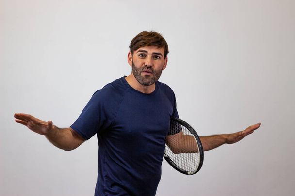 Πορτρέτο του όμορφος νέος άνθρωπος παίζοντας τένις κρατώντας μια ρακέτα w - Φωτογραφία, εικόνα