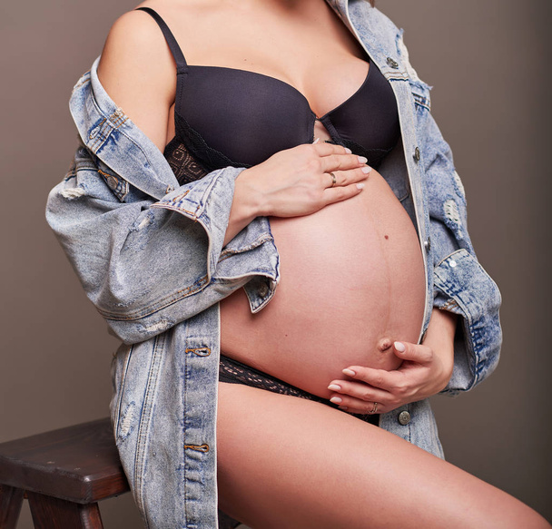 Terhes lány egy világos háttér. Fénykép arc nélkül a keretben. - Fotó, kép