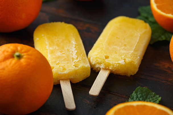 Homemade orange popsicles, ice lolly, on wooden table. Summer food. - Фото, изображение