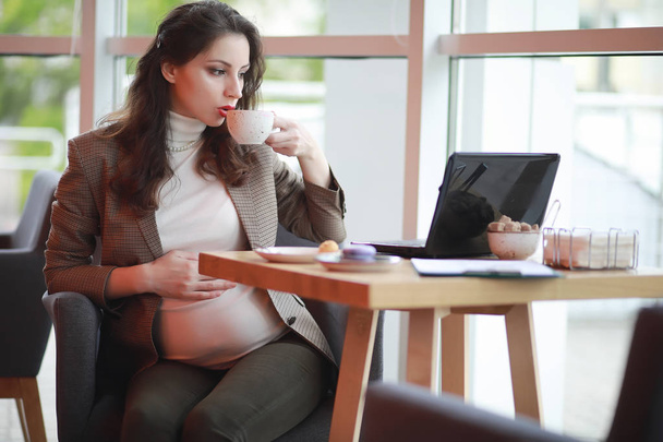 Pregnant woman working on computer in cafe - Фото, изображение