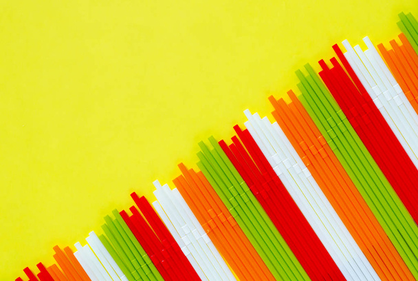 Красочные пластиковые соломинки на желтом фоне для летнего сезона
. - Фото, изображение