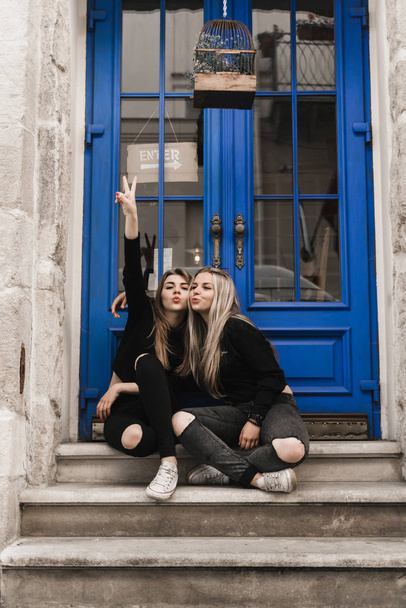 Attractive woman tourists in old european city. Beautiful young girl standing near the ancient blue door. Stylish teens traveling and enjoying summer time in Lviv, Ukraine. Girls in black enjoying summer - Fotoğraf, Görsel