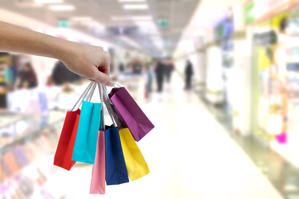 Crop main féminine tenant des sacs en papier coloré sur le fond du centre commercial
. - Photo, image