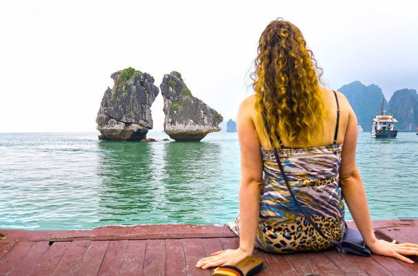 Πίσω άποψη γυναίκα ταξιδιώτης κάθεται στο σκάφος φαίνεται χαλαρή μεταξύ των νησιών στον κόλπο Χαλόνγκ, Βιετνάμ. - Φωτογραφία, εικόνα