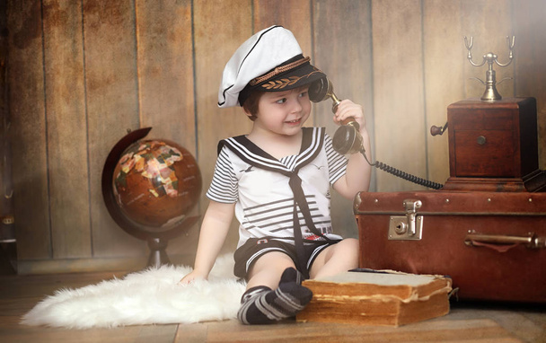 A child in a retro interior and an old phone sits on the floor.  - 写真・画像
