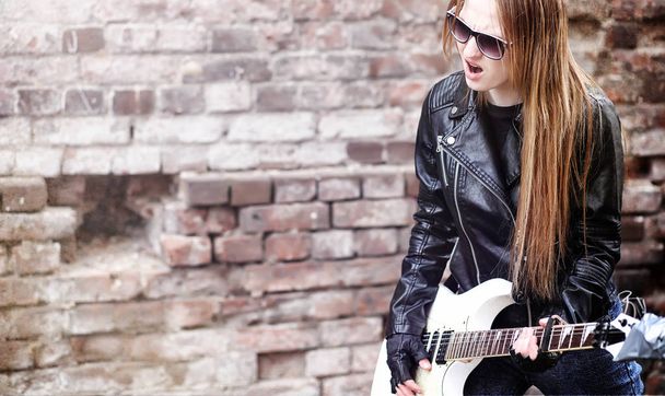 Beautiful young girl rocker with electric guitar. A rock musicia - Photo, Image
