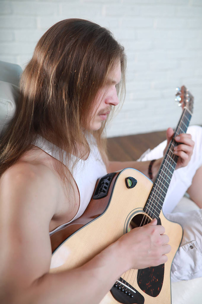 Joven con el pelo largo con una guitarra
 - Foto, Imagen