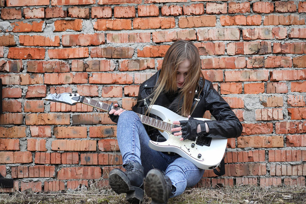  A rock musician girl in a leather jacket with a guitar  - Photo, Image