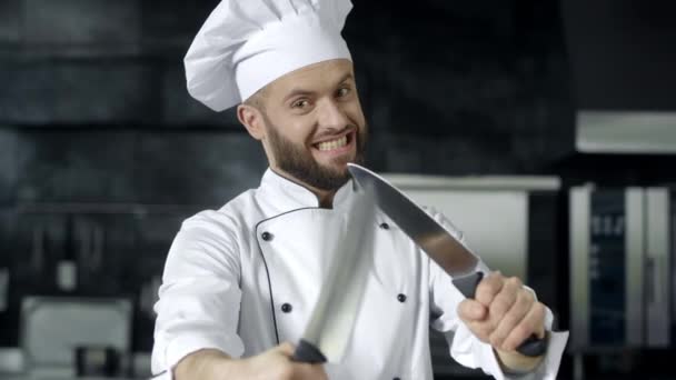 Kokki poseeraa veitsien kanssa keittiössä. Kokki mies hauskaa työkaluja keittiössä
. - Materiaali, video
