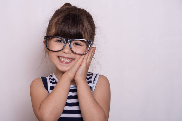 Grappig kind meisje dragen van een bril op een grijze achtergrond. - Foto, afbeelding