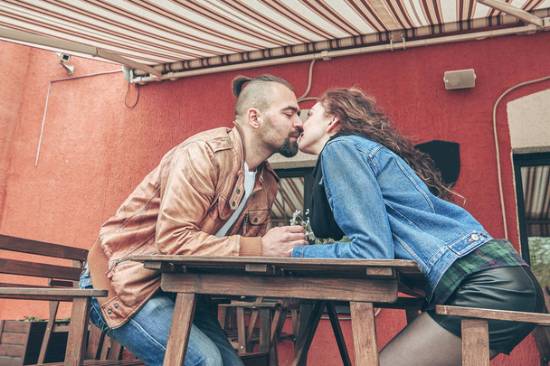 young couple kissing sitting at a table in a street cafe - Фото, изображение