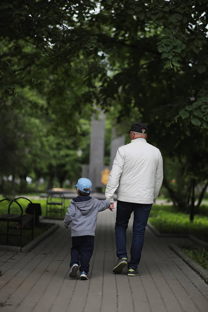 Περπατάει ο παππούς με τον εγγονό της σε ένα πάρκο την άνοιξη. Εγγονός  - Φωτογραφία, εικόνα